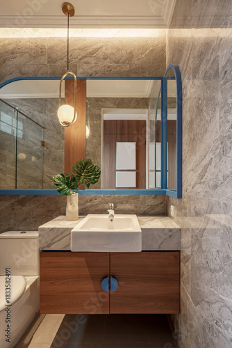 Modern luxury bathroom vanity with marble walls, wooden cabinet, and Monstera leaf decor.