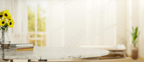 Fototapeta Naklejka Na Ścianę i Meble -  Coffee and book and sunflower vase on round marble table with sofa and window in bright living room.