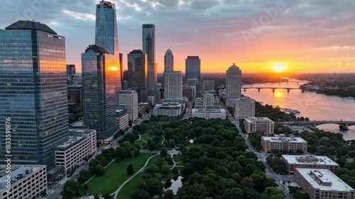 Sunset over newark new jersey downtown skyline with modern skyscraper cluster overlooking a large green park and river 4k video