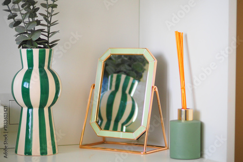 Decorative vase and mirror on a shelf in modern interior