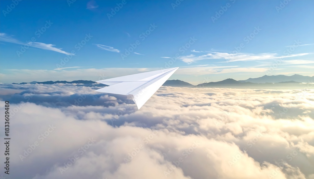 Obraz premium A white paper airplane soars above fluffy clouds under a bright blue sky with distant mountains
