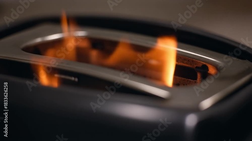 Toaster on fire with flames inside, kitchen appliance malfunction.