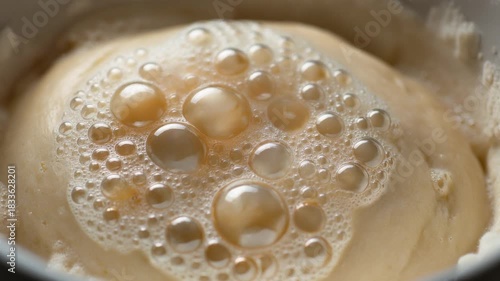 Close-up of a frothy beverage with many bubbles in a white cup.