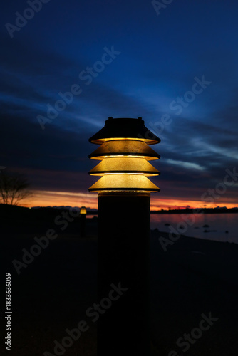 Lamplight by seaside walkway in morning twilight. Vertical view, copy space. 