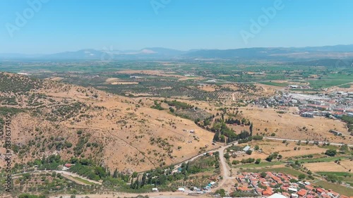 Bergama, Turkey. Flight over rural area with wooded slopes, dry grass, rustic huts and dirt roads on windy hot noon. Aerial view.