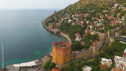 Alanya, Turkey. Historic Kizilkule Red Tower and ancient fortress wall meeting modern houses and marina, aerial drone view, summer.. Aerial View, MasterShots, Spiral forward