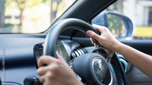 Action of a driver is gripping on steering wheel to control the car during driving. Transportation mode with close-up and selective focus on the hand.	