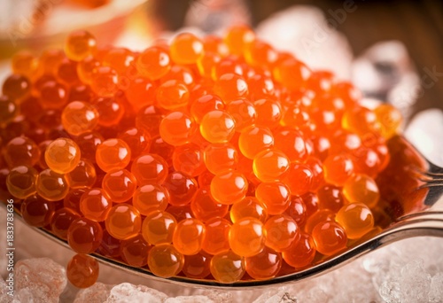 Vibrant orange salmon roe caviar served on a spoon with ice