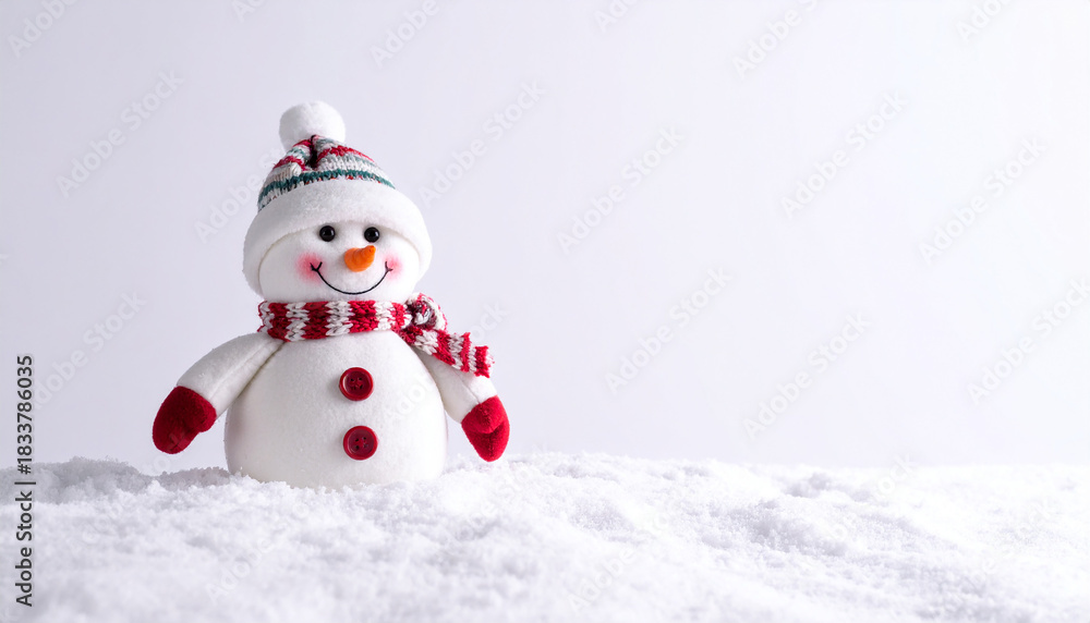 Fototapeta premium Cute Snowman Toy with Red Hat and Scarf on Real Snow Over a White Background