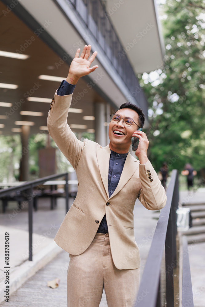 Fototapeta premium Asian businessman talking on phone and waving hand