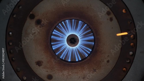 Close-up of a powerful industrial gas burner with a vibrant blue flame, symbolizing energy consumption and thermal heat production