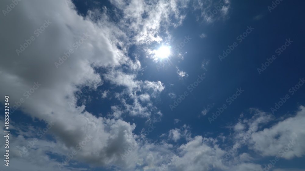 Fototapeta premium The sky is blue with a few clouds. The sun is shining brightly through the clouds. The sky is clear and bright