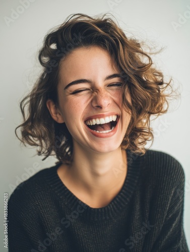 Woman with short curly hair laughing loudly with closed eyes. Happy emotion on female caucasian model face. Portrait for concept of joy.