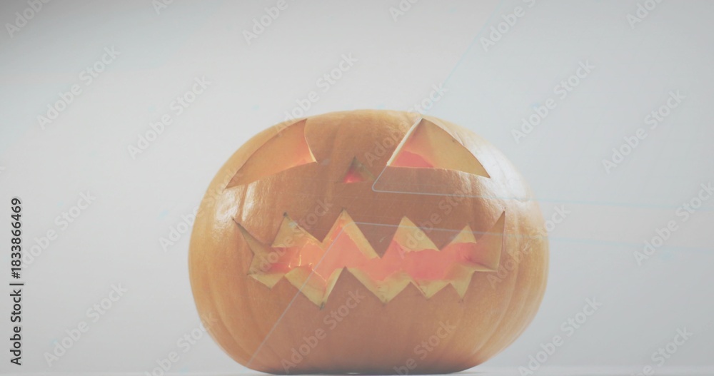 Obraz premium Glowing carved pumpkin emitting warm light, sitting on flat tabletop in pale gray studio backdrop