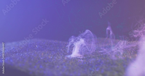 Rising single white smoke plume drifting over turf with dew under purple-blue lights in studio set