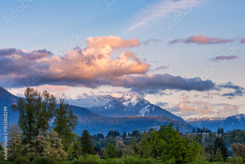 Snow capped mountains standing under a colorful sky at sunset