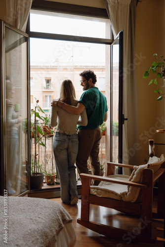 Wallpaper Mural A man smiles and hugs a woman standing next to him while they look out the window Torontodigital.ca