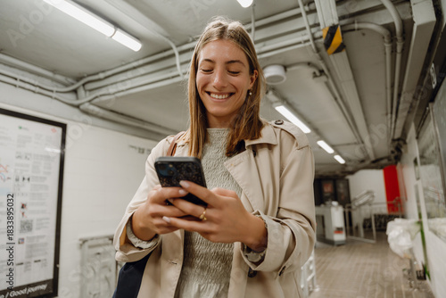 Принти на полотні Woman typing on phone while walking down hallway and smiling
