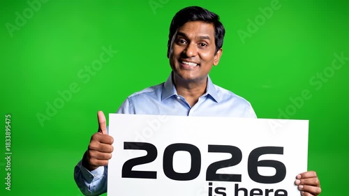 Man holding a sign that says 2026 is here with a green screen background.