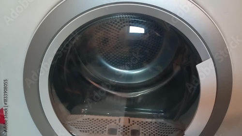 Electric dryer starts with high frequency sound and drum rotation close up on door during operation
