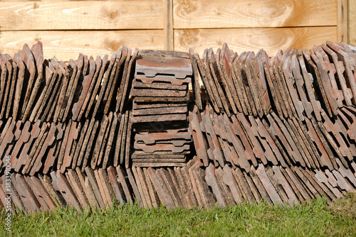 Stack of Salvaged Red Clay Roof Tiles against Wooden Fence