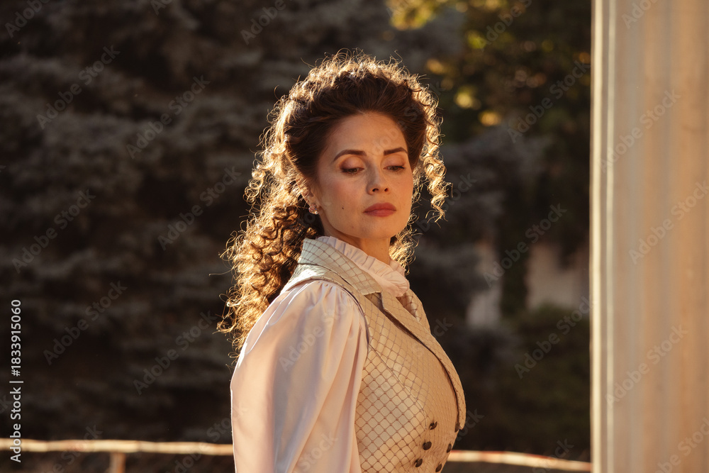 Fototapeta premium Portrait of a woman in vintage clothing, illuminated by warm sunlight, against a backdrop of ancient architecture.