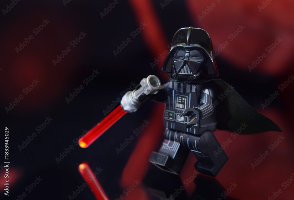 Naklejka premium Lego minifigure of Darth Vader from Star Wars with lightning sword is walking. Editorial illustrative image of toy from popular children construction