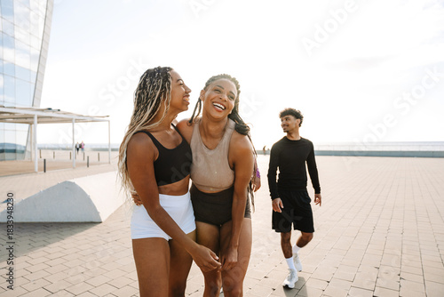 Canvastavla A female athlete hugs a female athlete and they laugh as a male athlete follows