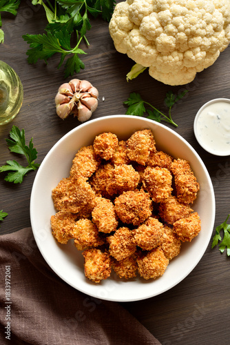 Breaded oven baked cauliflower bites in bowl on wooden table