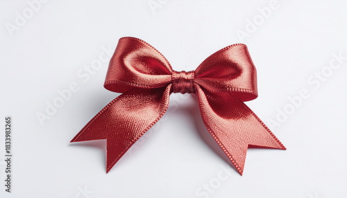 Shiny red satin ribbon bow with pointed ends against a clean white background decorative gift present
