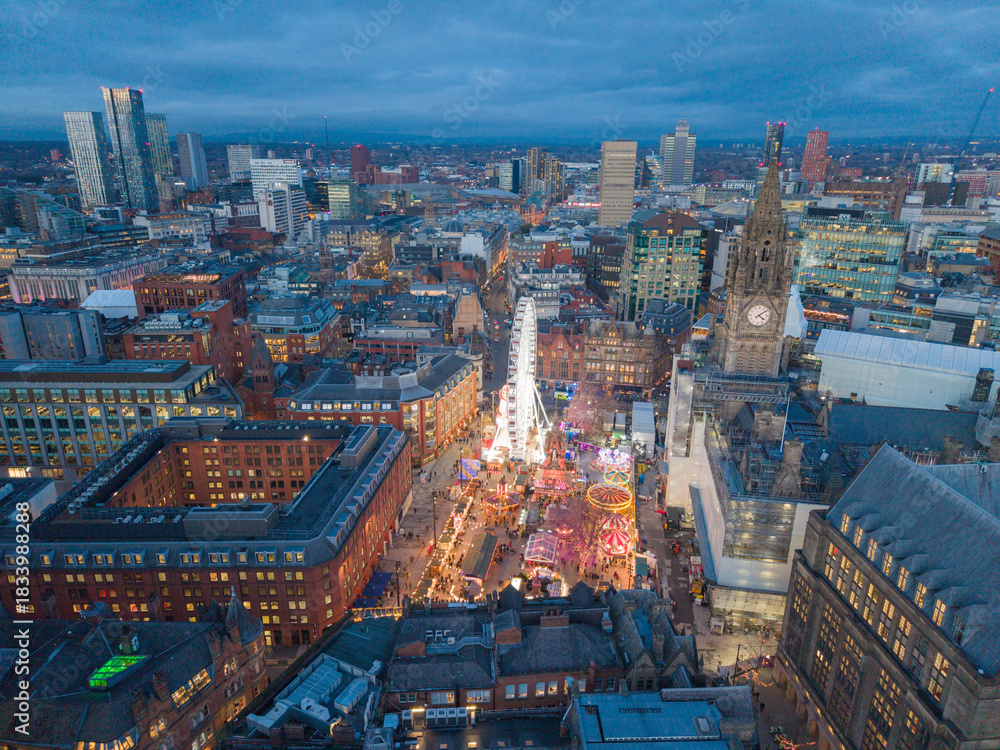 Obraz premium Aerial dusk view of Manchester skyline with Albert Square Christmas market, bright wheel and glowing festive winter streets.