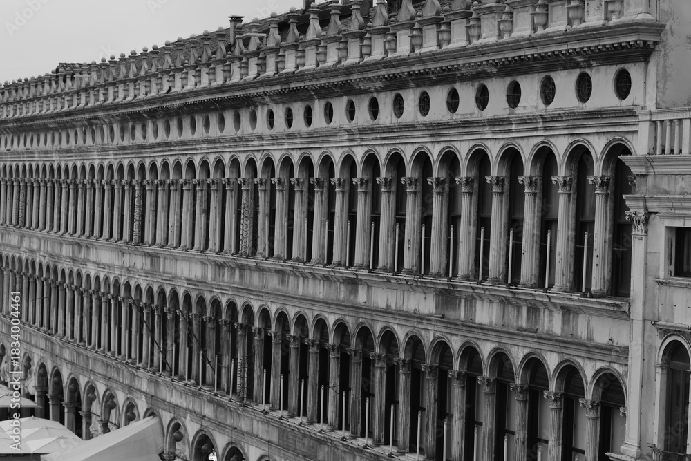 Fototapeta premium Historic Renaissance building with rows of arches and columns on Piazza San Marco in Venice, Italy. Elegant symmetrical architecture in monochrome tones.