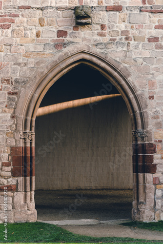 Intricate stone archway welcomes visitors to a serene courtyard with warm sunlight streaming inside in a historic site