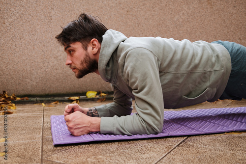 A man holds a plank position on a purple mat. The posture reflects discipline and steady physical control.