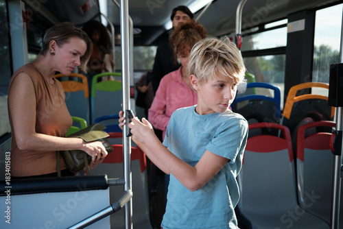 Boy using mobile phone traveling with family on bus