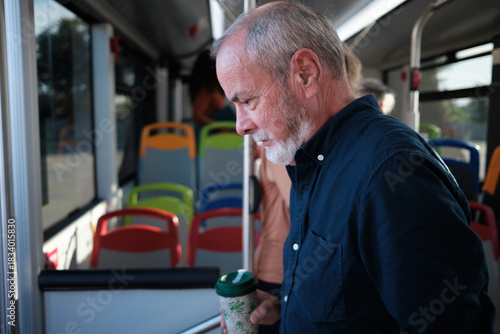 Senior man commuting on public transport with reusable cup