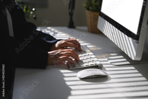 Hands typing on keyboard under soft window shadows, expressing focus and quiet productivity