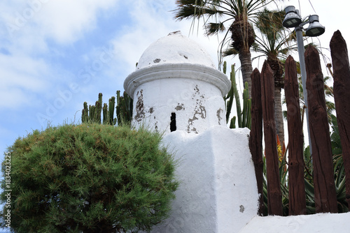 Old White Painted Circular Stone Watch Tower with Palm Trees and Wooden Fence 