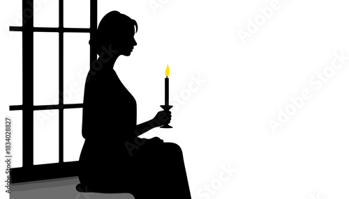 Silhouette of woman sitting with candle by window in dark room  
