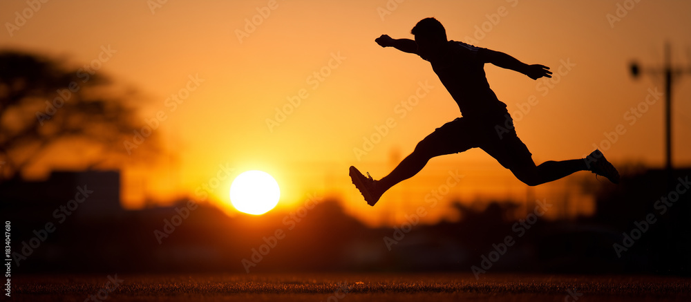 Obraz premium Silhouette of a man leaping in front of a vibrant sunset banner.