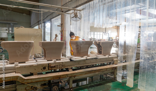 Workers moving ceramic bathroom components in a production workshop