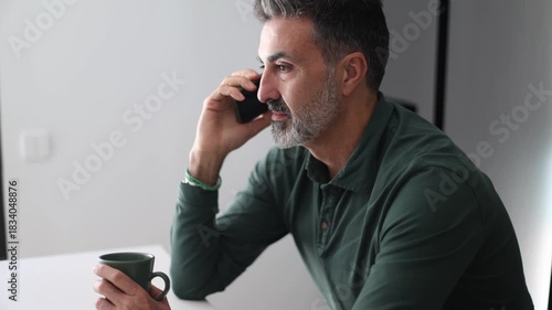Mature man with beard talking on a cellphone at home
