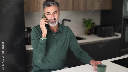 Stressed mature man arguing angrily on a phone call at home
