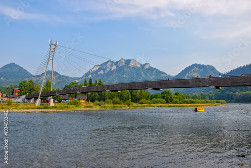 Fototapeta Naklejka Na Ścianę i Meble -  Modern bridge across Dunajec river - popular tourist spot for boat rafting - in Pieniny National Park., Poland at sunny day. Trzy Korony (Three Crowns) summit in the background