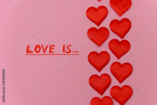 Red hearts arranged on a pink background with the text 'Love is...'. The scene conveys a romantic theme, suitable for Valentine's Day or love-related concepts.