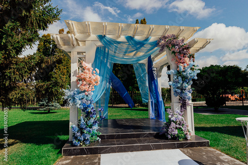 Elegant outdoor wedding altar decorated with floral arrangements and blue drapery