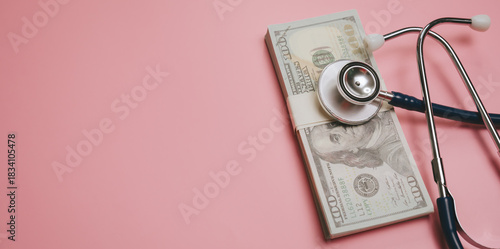Medical cost concept with stethoscope on stack of hundred dollar bills on pink background, symbolizing healthcare expense and financial health management