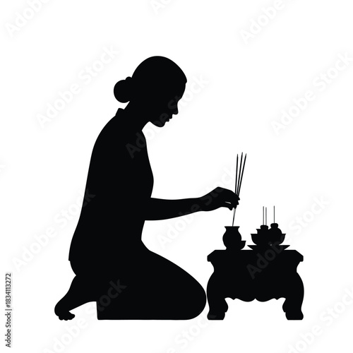 Woman kneeling and lighting incense sticks silhouette