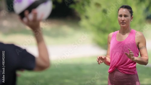 Woman and man playing catch with a ball in a park