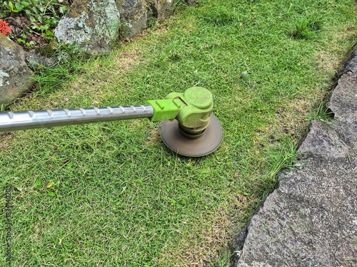 Photos Electric grass trimmer edging a green lawn near stone pathway, precise garden ma